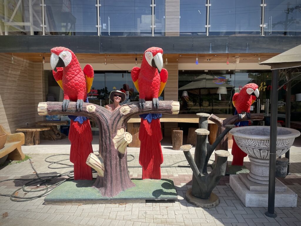 Mrs. ItchyFeet behind macaw sculpture