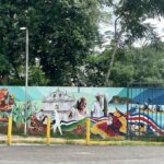 Nicoya mural of church, Costa Ricans, farmers, biker, kayakers, scarlet macaw