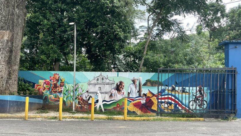 Nicoya mural of church, Costa Ricans, farmers, biker, kayakers, scarlet macaw