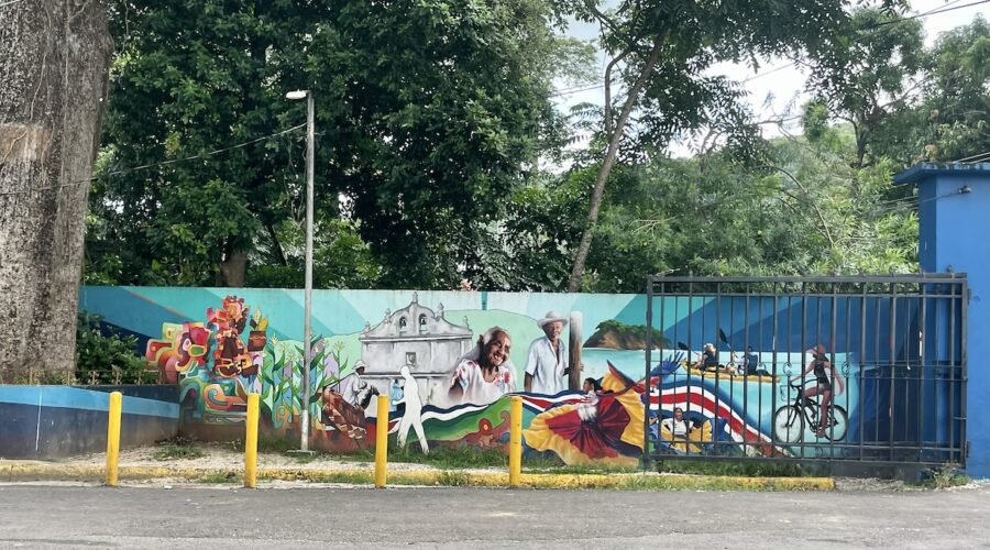 Nicoya mural of church, Costa Ricans, farmers, biker, kayakers, scarlet macaw