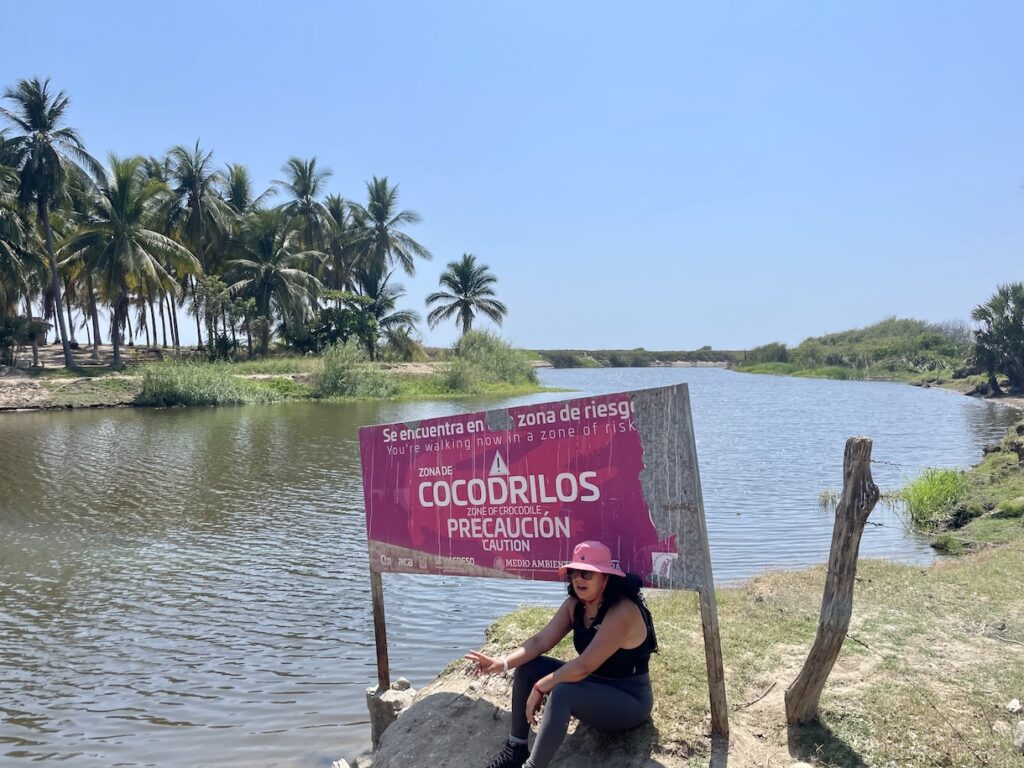 Hiker resting in front of crocodile warning sign