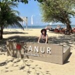 Mrs. ItchyFeet behind Sanur letters