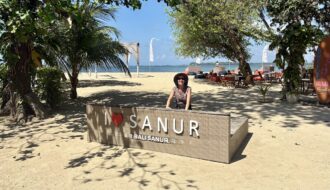 Mrs. ItchyFeet behind Sanur letters