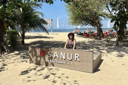 Mrs. ItchyFeet behind Sanur letters