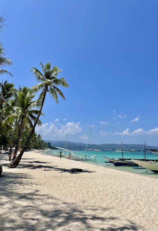 Palm trees and sailboats along White Sand Beach in Boracay